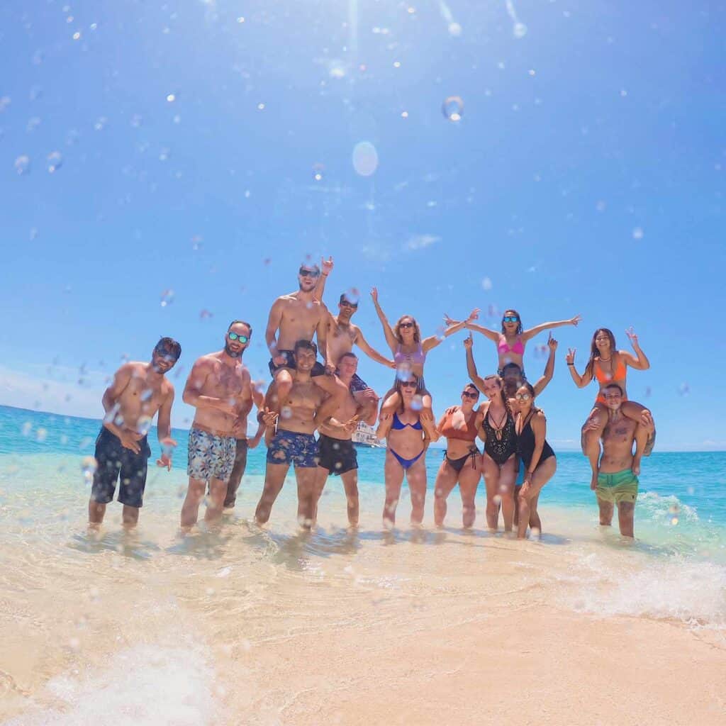 Group of friends having fun on the beach with clear blue sky and ocean in the background.