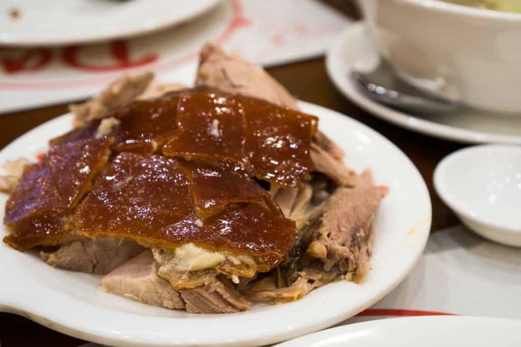 Delicious roasted pork with crispy crackling served on a white plate.