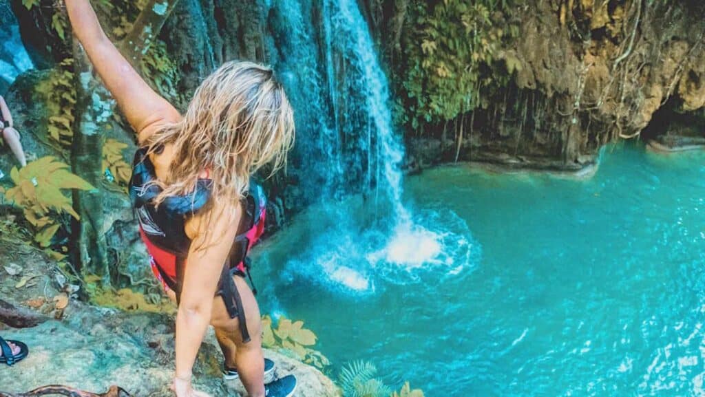 Waterfall cascading into a turquoise pool at Mitte Hostel, Berlin, with lush greenery surrounding th.
