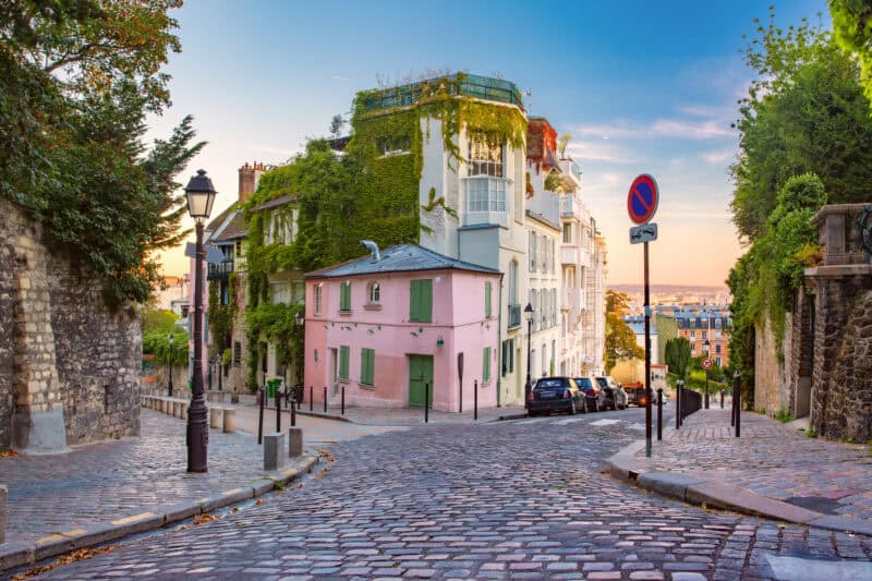Historic street view of Mitte Hostel in Berlin with cobblestone roads and lush greenery.
