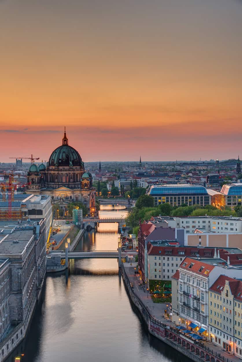 Historic St Christopher's Church with Berlin cityscape at sunset.