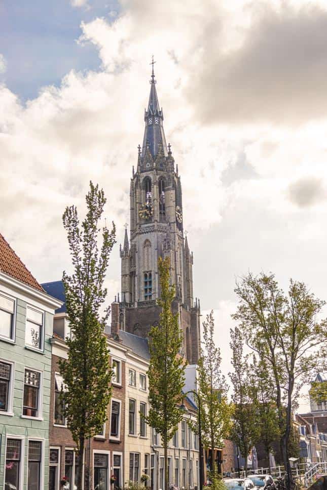 Historic church tower in Berlin with surrounding trees and traditional buildings.