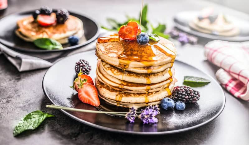A stack of fluffy pancakes with berries and syrup, perfect for breakfast at St Christopher’s Berlin.