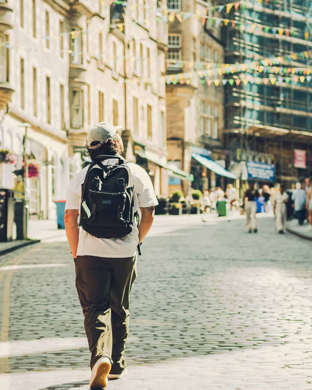 Person walking in a city street with backpack, historic buildings in the background.