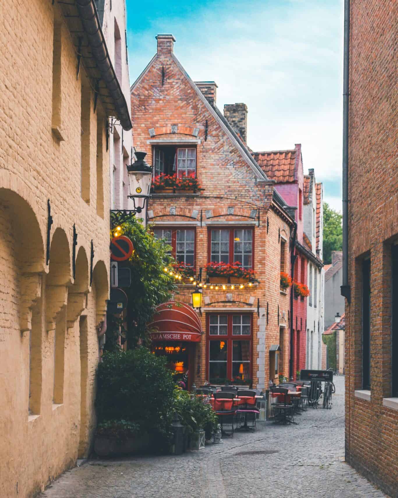 Historic pub in a narrow alleyway with outdoor seating and vibrant flowers.