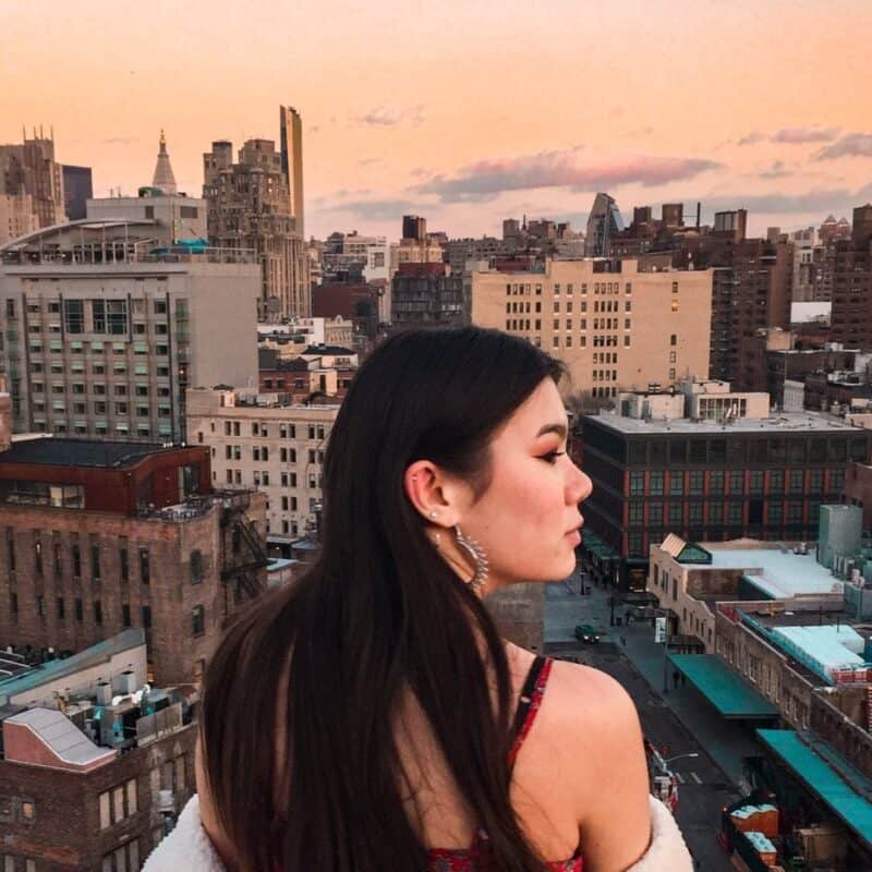 Woman overlooking New York City skyline at sunset, cityscape background.
