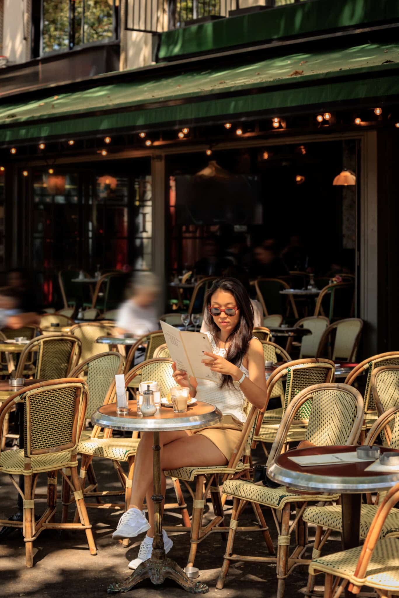Traveller relaxing at a sunny Paris café terrace – stay at the best youth hostels in Paris and live the city like a local