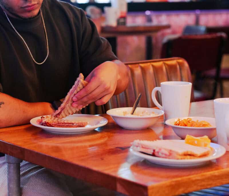 Bacon, eggs, and toast breakfast served on a wooden table in a casual dining setting.