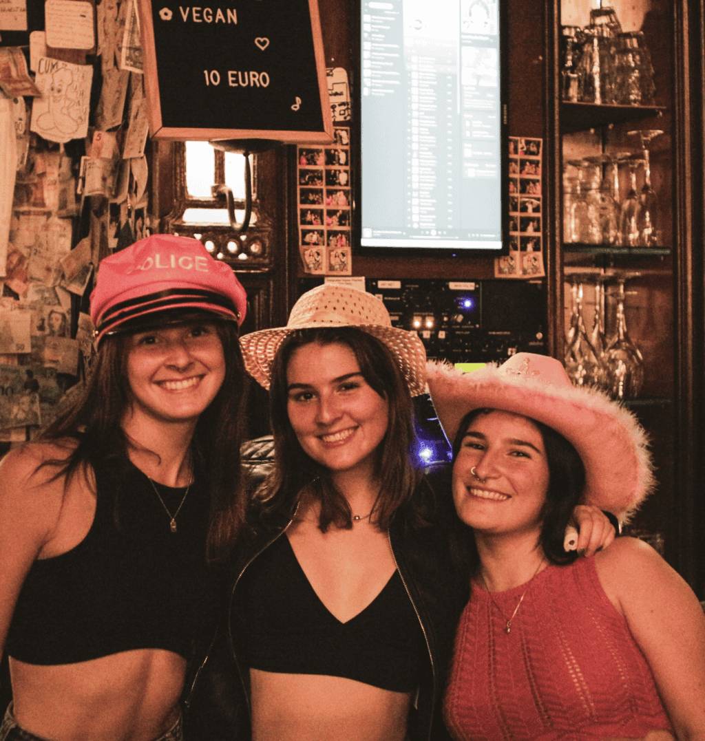Group of three women wearing playful hats at St Christopher's pub, enjoying a night out.