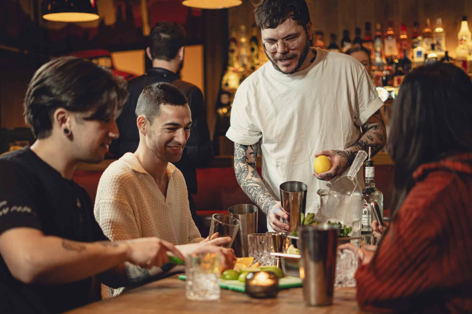 People enjoying cocktails at a lively bar with bartender serving drinks.