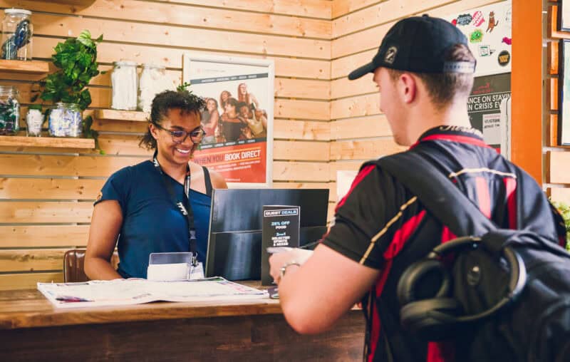 Friendly receptionist assisting a guest at St Christopher's hostel reception.