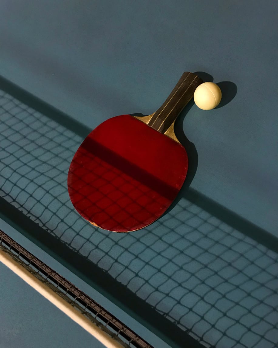 Ping pong paddle and ball for table tennis on blue surface.