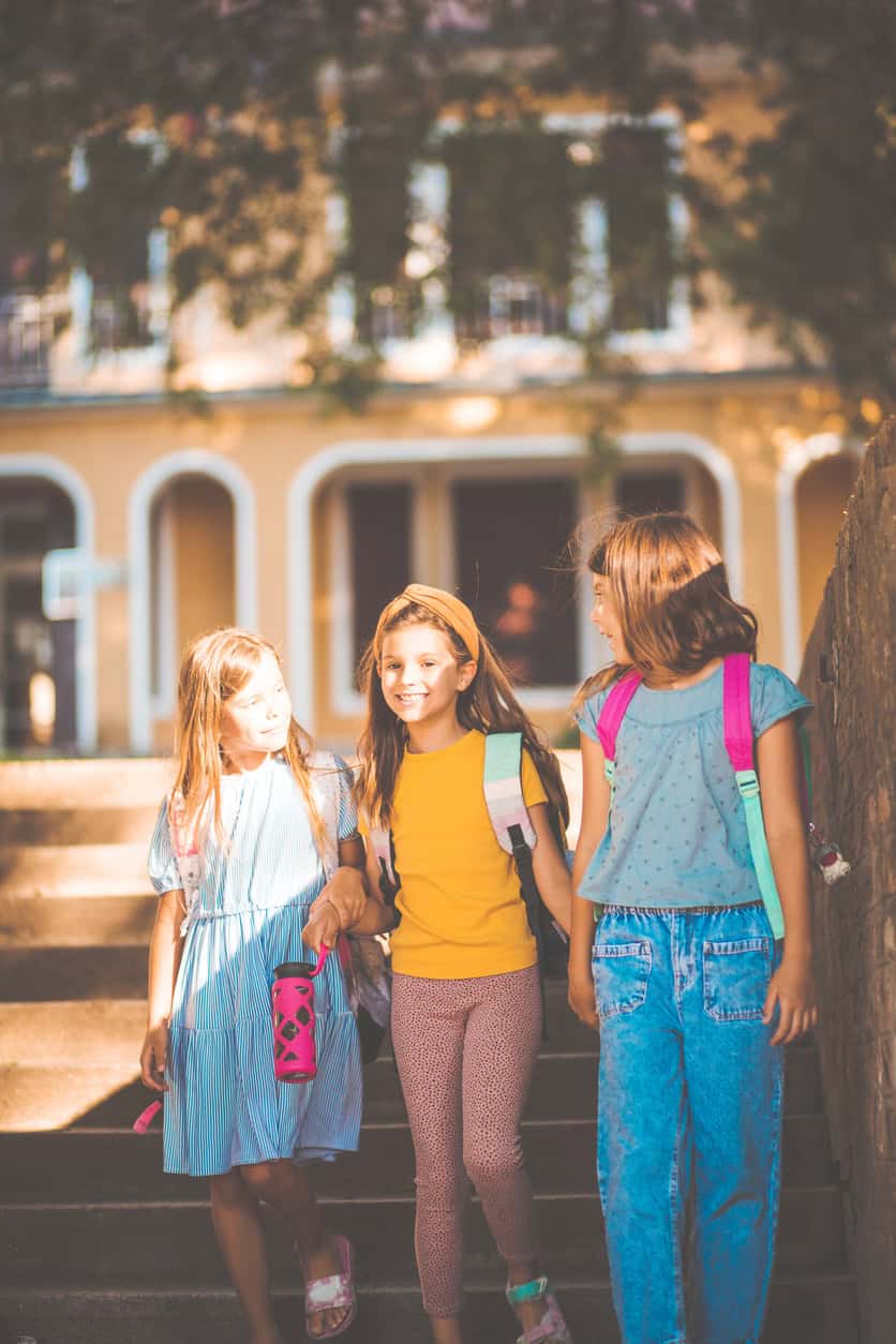 Children walking to school outside St Christopher's building, smiling and chatting.