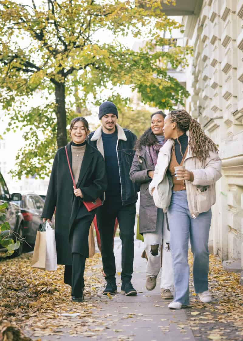 Group of diverse students walking outdoors on a university campus in autumn.