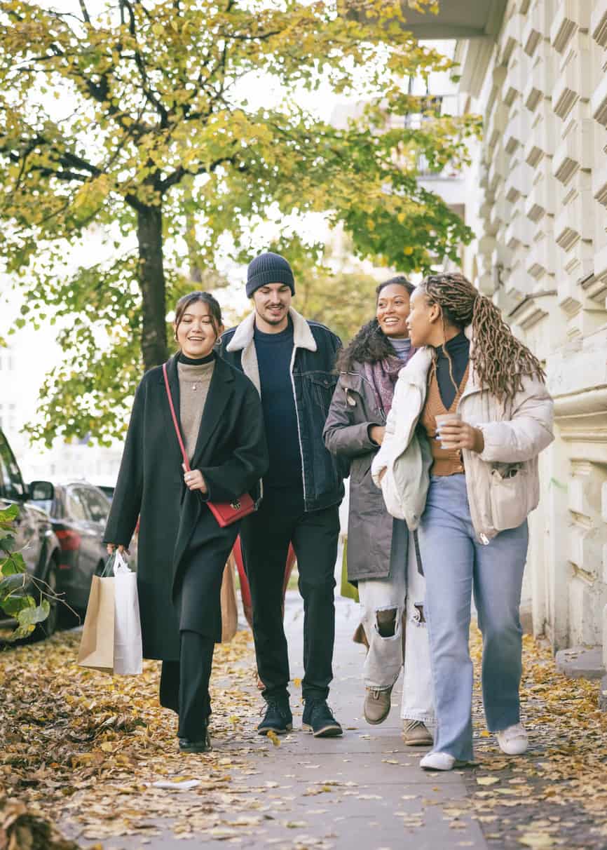 Group of diverse students walking outdoors on a university campus in autumn.
