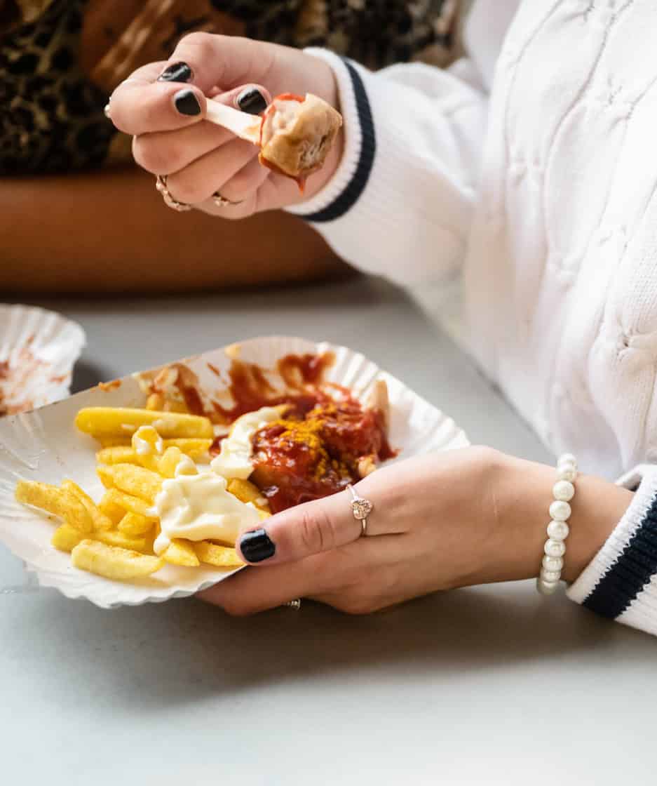 Person holding a plate with fries, chicken nuggets, and sauce.