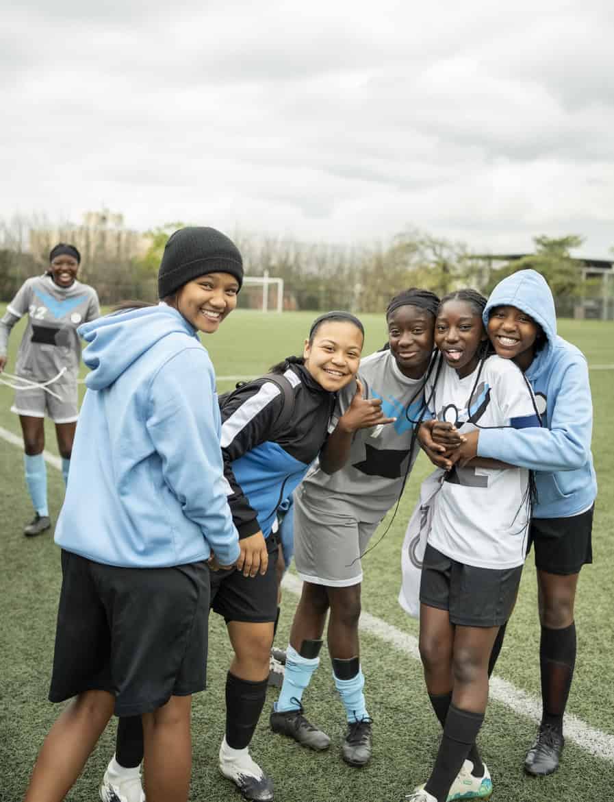 Group of diverse young athletes smiling on a sports field in sportswear.