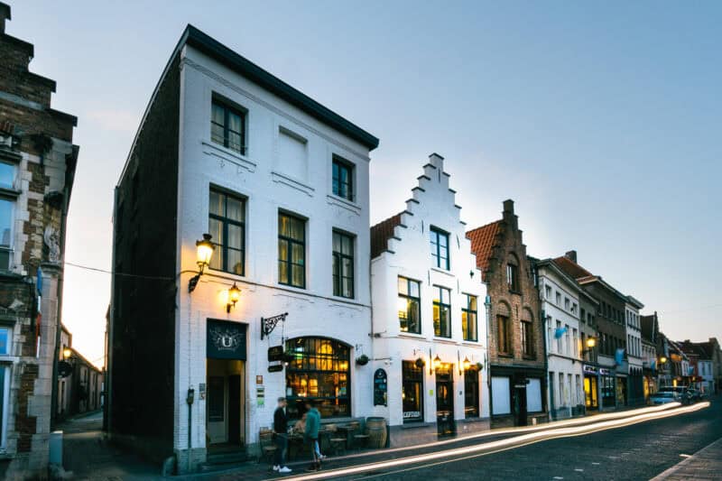 Historic Bauhaus-style building on a Bruges street at dusk, illuminated by streetlights.