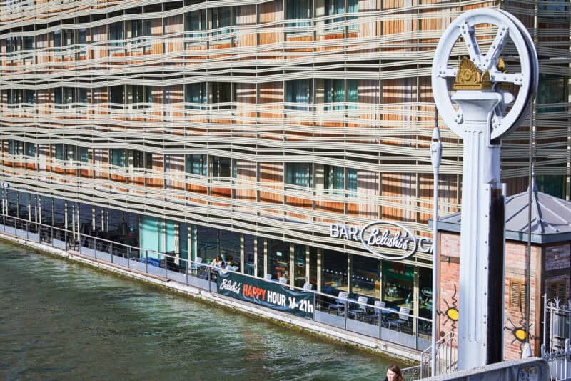 Modern canal-side building with colourful exterior and bar signage, located in Paris.